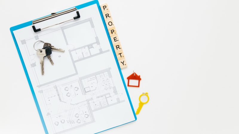 A clipboard displaying keys and a house plan, set against a clean white background